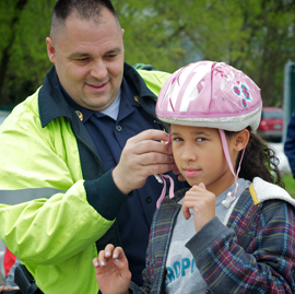 Police officer helping student with helmet
