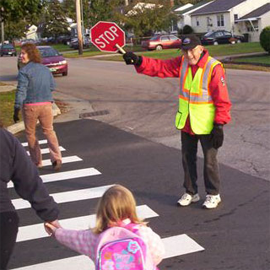 A crossing guard helps students cross at the crosswalk
